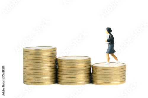 Miniature people toy figure photography. School admission budget concept. Young girl pupil running above golden coin cent money staircase, isolated on white background