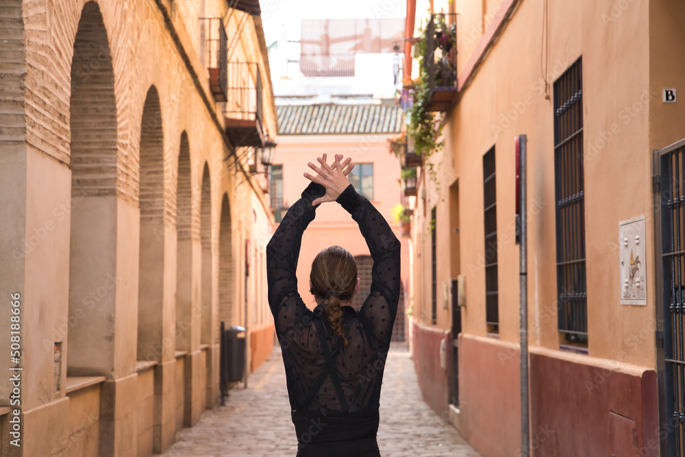 Young man with beard and ponytail, wearing black transparent shirt with black polka dots, black pants and jacket, dancing flamenco in the city. Concept art, dance, culture, tradition.