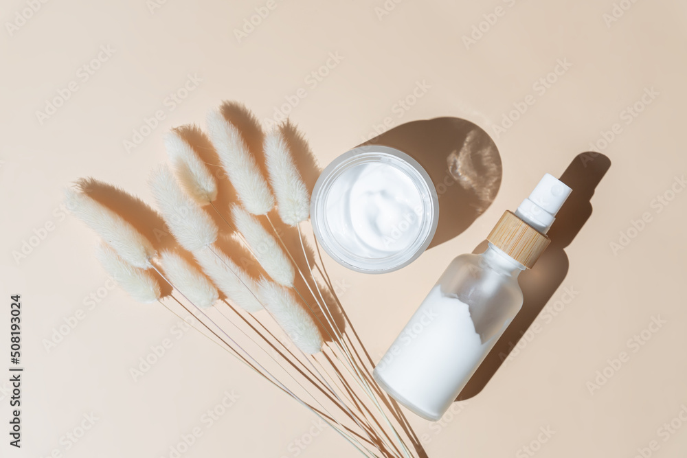 Face and eye moisturizer cream and serum in a glass bottle and jar and dried herb on light beige background. Concept eco organic natural cosmetic products for skincare Face and eye moisturizer cream and serum in a glass bottle and jar and dried herb on light beige background. Concept eco organic natural cosmetic products for skincare