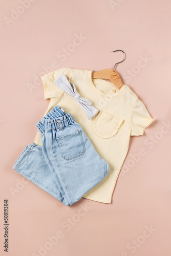 Childish image with jeans and a yellow t-shirt on a pink background.