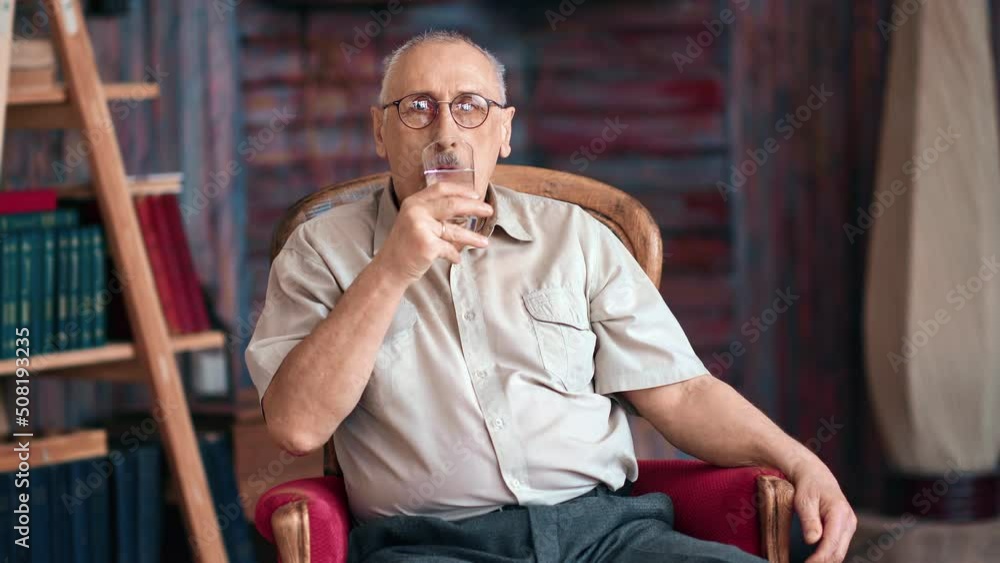 Portrait smiling aged man drinking fresh pure water healthy lifestyle sitting on vintage armchair Portrait smiling aged man drinking fresh pure water healthy lifestyle sitting on vintage armchair