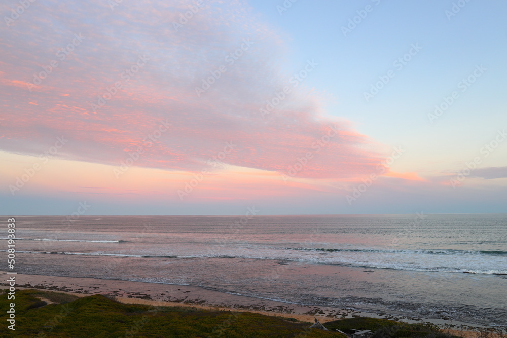 A sunset view over the coastline at Witsand, South Africa, with pink clouds and blue skies.