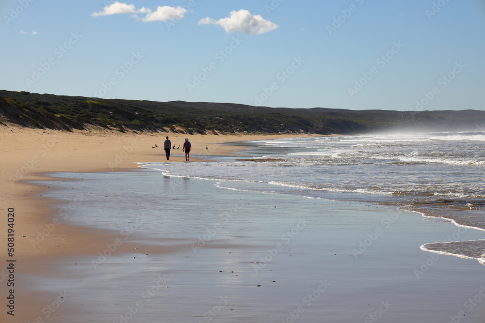 Two females walking along a sandy beach at Witsand, Western Cape, South Africa.