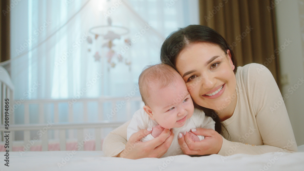 Concept of maternity childhood and health nursing care mother take the baby girl from the bed and start to play with the baby in front of the camera Concept of maternity childhood and health nursing care mother take the baby girl from the bed and start to play with the baby in front of the camera