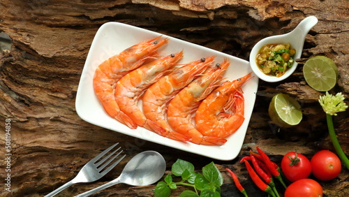 Steamed shrimp with sauce and vegetables on wooden background