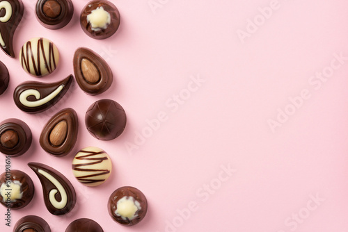 Chocolate pralines on pink background, flat lay, top view with copy space	