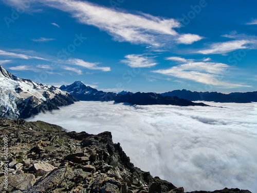 Sea of clouds hanging over the valley in front of Mount Cook, New Zealand. Rough gravel and stones in the foreground. 