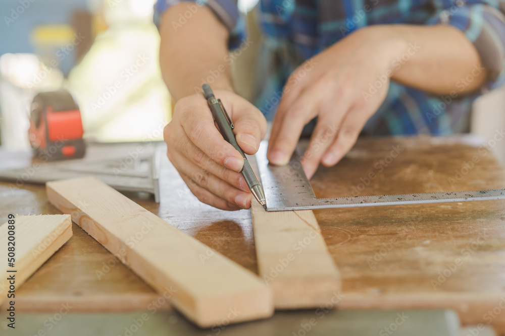 Carpentry professional, hand of asian young man, male carpenter use ruler measure, tool on board wood in small shop. Woodwork, furniture making, construction industry. Owner small business people. Carpentry professional, hand of asian young man, male carpenter use ruler measure, tool on board wood in small shop. Woodwork, furniture making, construction industry. Owner small business people.