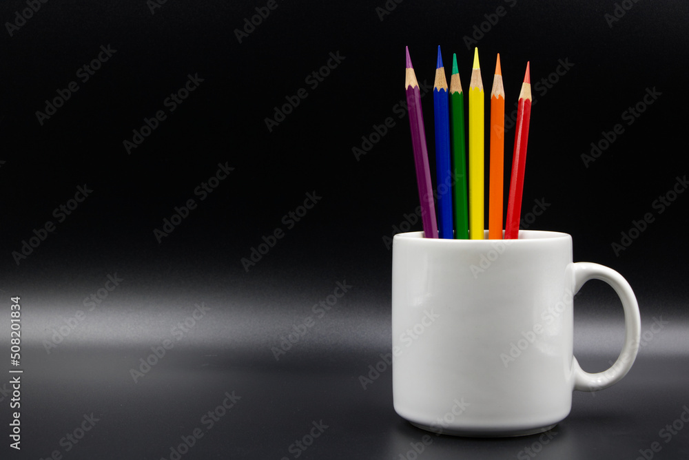 Crayon, a color symbol of LGBT pride, in a white pitcher on a black background. Crayon, a color symbol of LGBT pride, in a white pitcher on a black background.