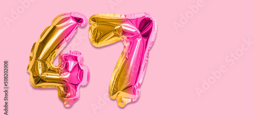 Rainbow foil balloon number, digit forty seven on a pink background. Birthday greeting card with inscription 47. Top view. Numerical digit. Celebration event, template. Banner