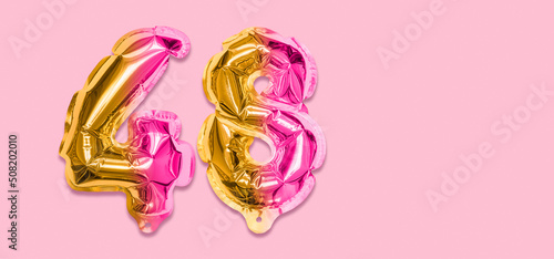 Rainbow foil balloon number, digit forty eight on a pink background. Birthday greeting card with inscription 48. Top view. Numerical digit. Celebration event, template. Banner