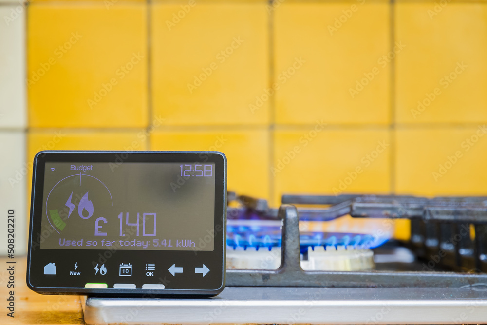 Smart meter placed next to gas stove with blue flames burning Smart meter placed next to gas stove with blue flames burning