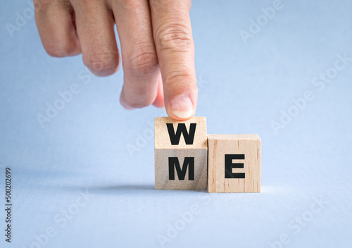 Fotografija Fingers flip wooden cube with word me to we. Teamwork concept.