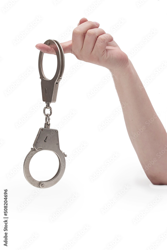 Metal handcuffs with a chain on a light background in a female hand Metal handcuffs with a chain on a light background in a female hand