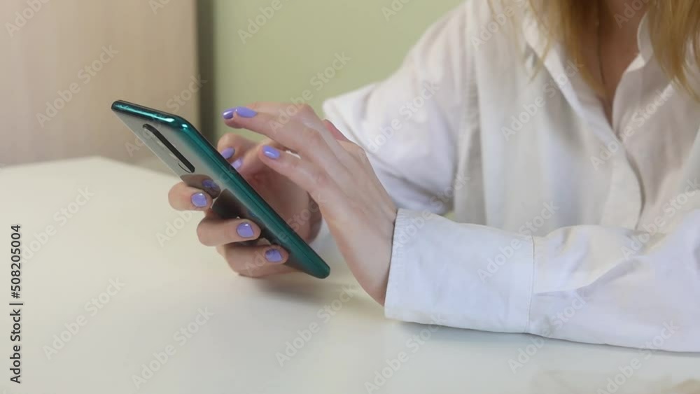 A girl sits with her phone at her desk and works. A girl sits with her phone at her desk and works.