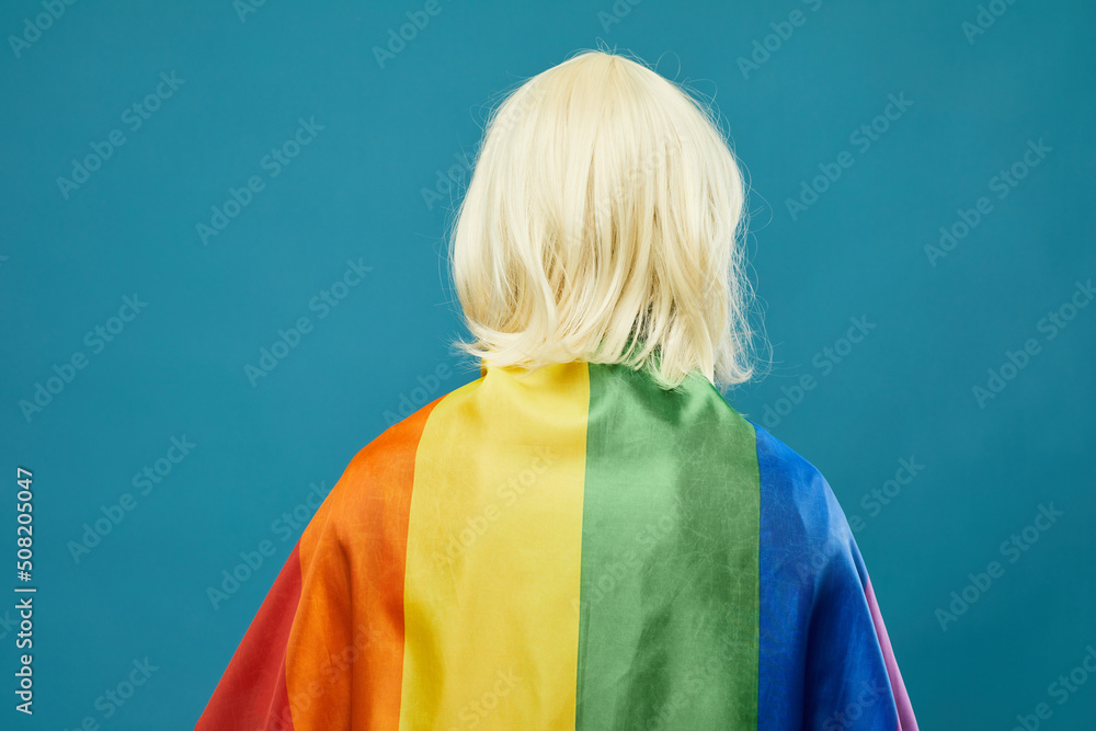 Back view of person rainbow flag against vibrant blue background LGBTQ pride Back view of person rainbow flag against vibrant blue background LGBTQ pride