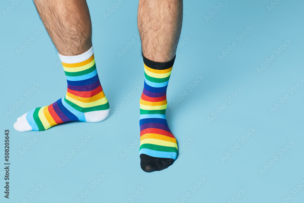 Minimal shot of man wearing mismatched socks on pastel blue background, copy space Minimal shot of man wearing mismatched socks on pastel blue background, copy space
