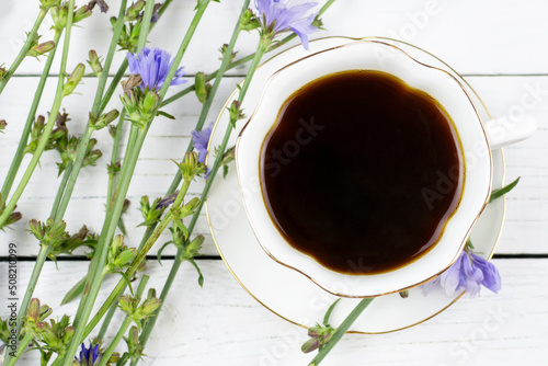 Canvas Print Beautiful cup on a saucer with a chicory drink on a white wooden background, top view