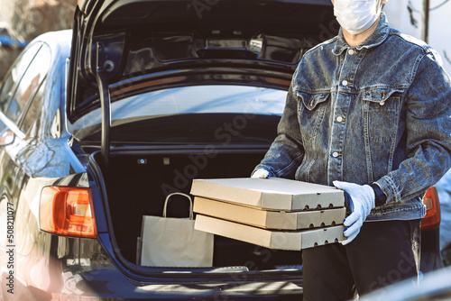 delivery food, man holding boxes of food in his hands, isolated on brown background