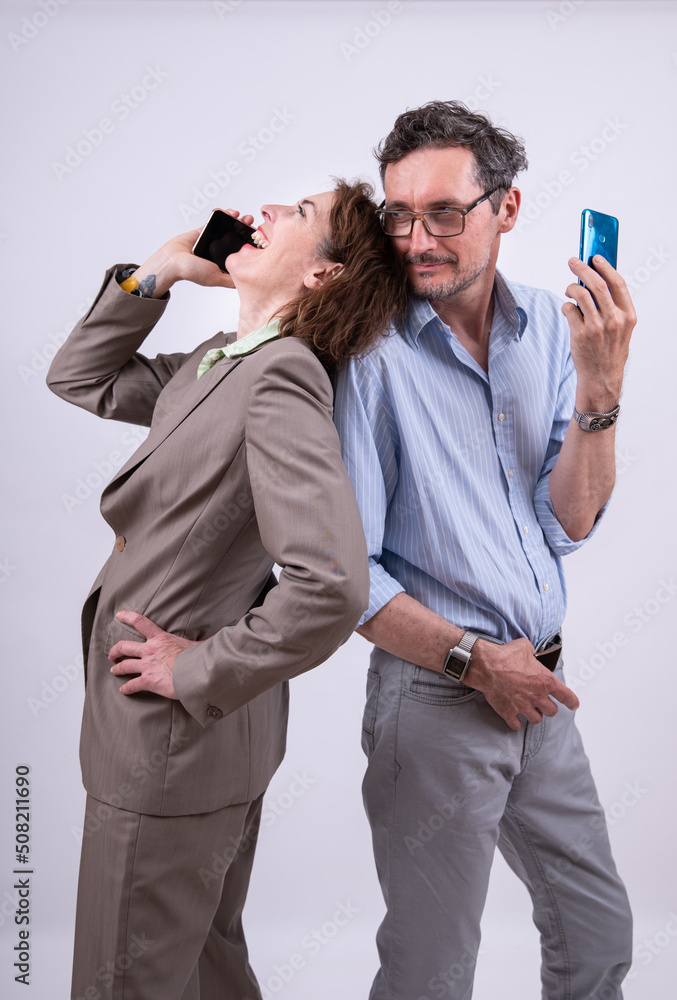 Frau telefoniert lachend, Mann mit Handy blickt lächelnd über die Schulter