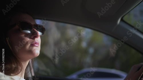 Young woman taxi driver with glasses riding at sunset, side view