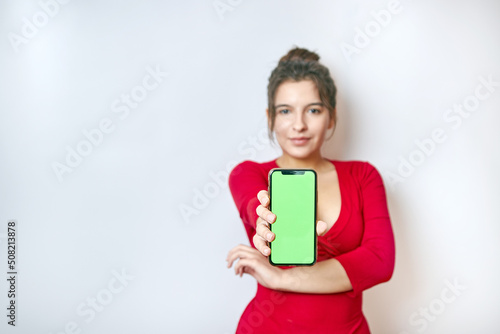 Pretty girl holding a smartphone with a green display. Demonstration of the image on the smartphone screen.