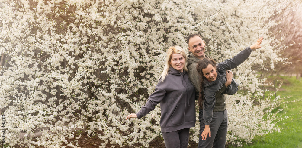 family having fun with flowering tree in blooming spring garden