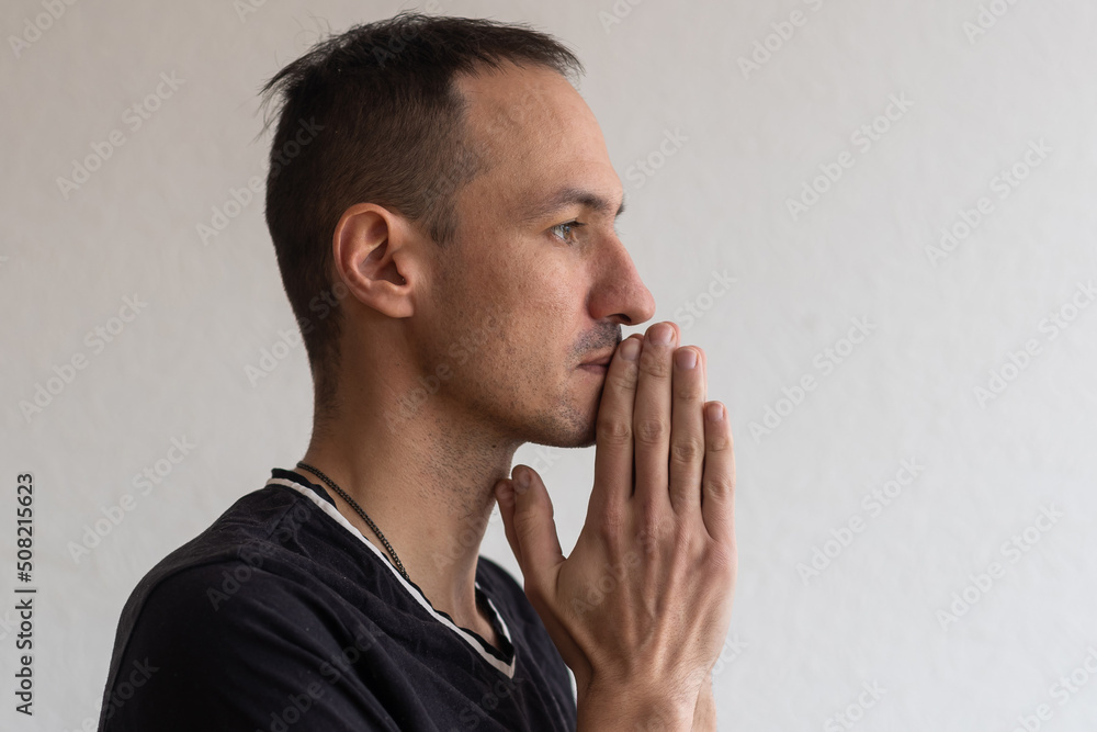 Photo man looks with interest expression aside, keeps hand near lips. Beautiful young man isolated on white background in Studio with an empty space for text and advertising Photo man looks with interest expression aside, keeps hand near lips. Beautiful young man isolated on white background in Studio with an empty space for text and advertising