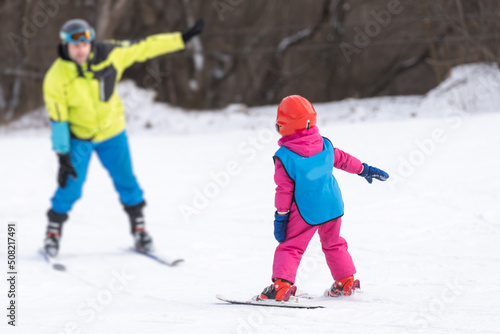 Instructor and little child skiing. toddler kid with safety helmet. Ski lesson for young children. Winter sport. Little skier