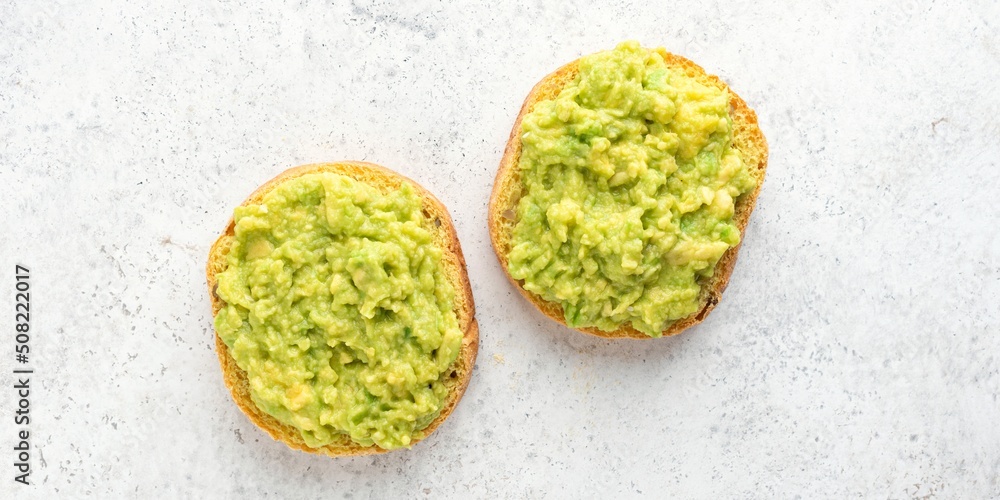 Vegan english muffin toast with mashed avocado on grey concrete background, top view. Banner Vegan english muffin toast with mashed avocado on grey concrete background, top view. Banner