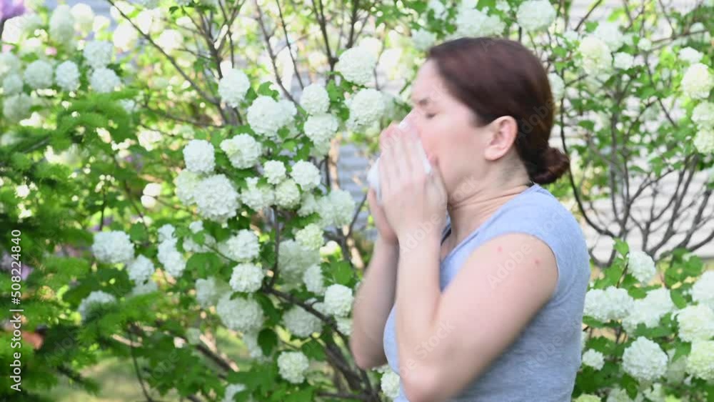Caucasian woman suffers from allergies and sneezes while walking in the park. Caucasian woman suffers from allergies and sneezes while walking in the park.