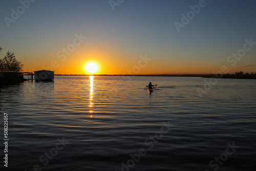 forces a guy swimming in a kayak at sunset. water sports. summer vacation on the water
