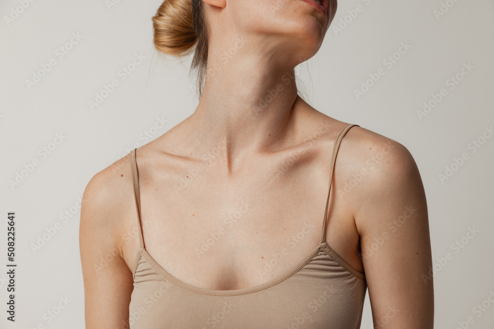 Beautiful female body, breast in cotton beige underwear posing isolated over grey studio background. Tender collarbone. Beautiful female body, breast in cotton beige underwear posing isolated over grey studio background. Tender collarbone.