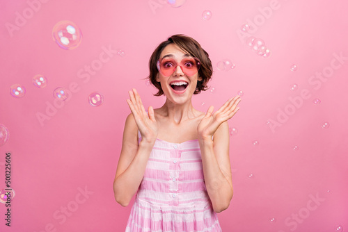 Photo of young excited girl good mood surprise air bubbles playful eyeglasses isolated over pink color background