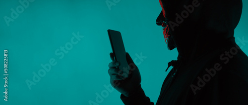 Tela Anonymous hacker and face mask with smartphone in hand