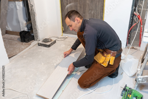 carpenter worker installing laminate flooring in the room.