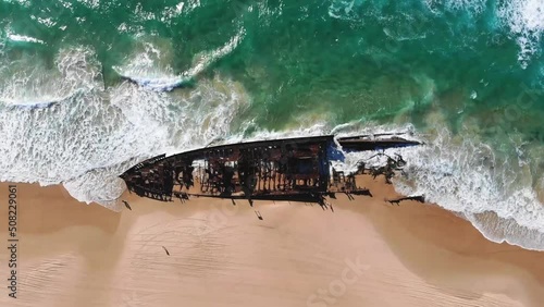 Top aerial view of abandoned and rusty boat wreck in the sea shoere of the ocean photo