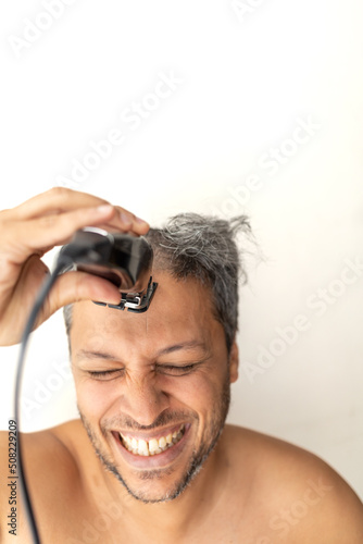 Handsome gray-haired man is cutting hair himself.