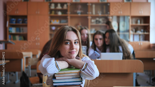 A student poses with textbooks at her desk in her class. © Довидович Михаил