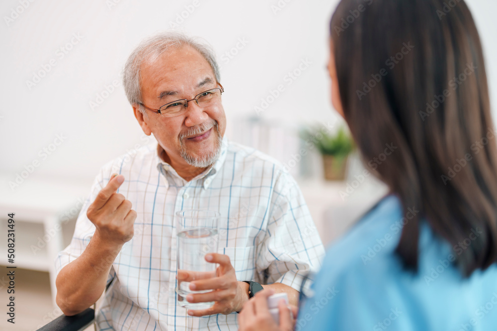 Female caregiver giving the medicine to her older male patient.