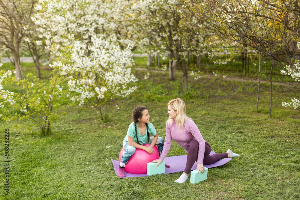 Fototapeta premium Mother and her daughter outdoors doing yoga, healthy lifestyle.