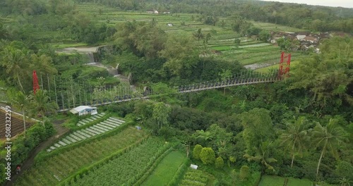 aerial drone view of suspension bridge, the valley and river with waterfall. mangunsuko bridge or Jokowi bridge with Merapi volcano on the background. infrastructure building videos photo