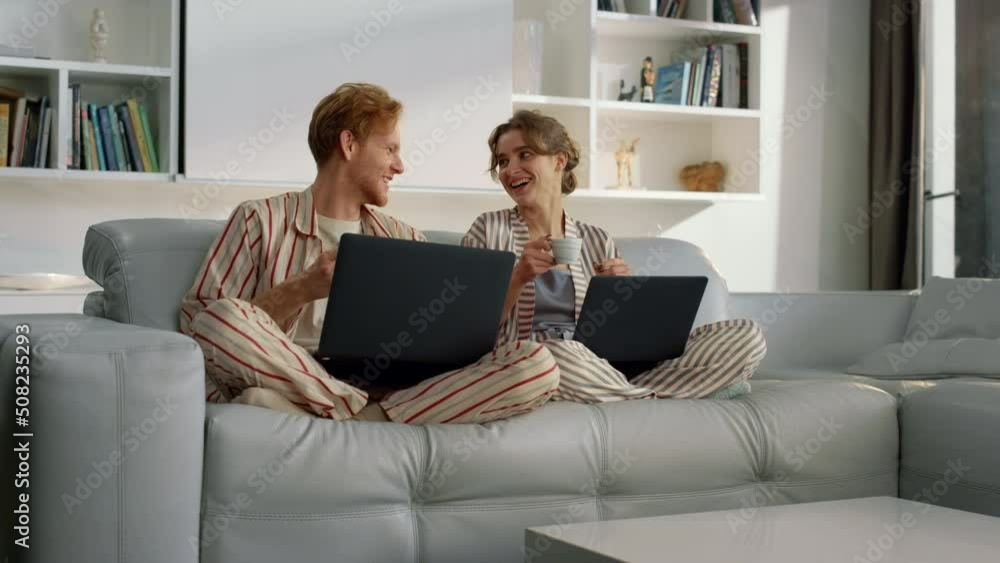 Happy couple using laptops resting on weekend. Young people work in home office