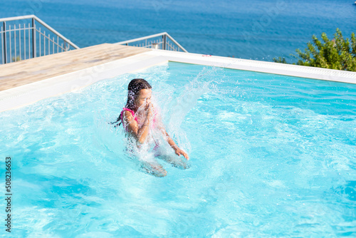 Closeup portrait of cute little arabic girl swimming in the pool  happy child having fun in water  beach resort  summer vacation and holidays concept