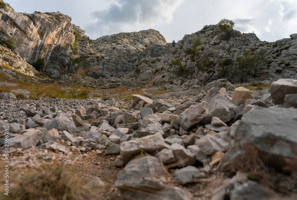 ground-level view of out-of-focus stones on a slope with mountains in focus in the background ground-level view of out-of-focus stones on a slope with mountains in focus in the background