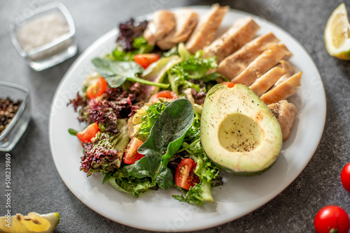 Grilled chicken meat and fresh vegetable salad of tomato, avocado, lettuce and spinach. Healthy and detox food concept. Ketogenic diet.