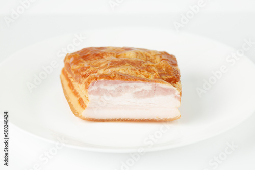 Smoked appetizing pork belly on a white plate.