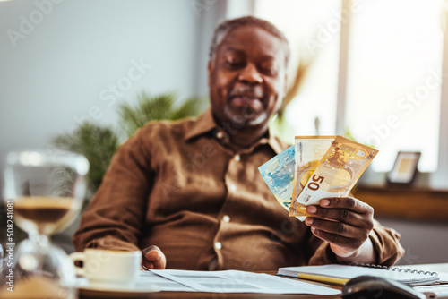 Worried senior man reading bad news in paper letter document feels disappointed, stressed old man troubled with high taxes or domestic bills, concerned about bank debt, financial problem concept photo