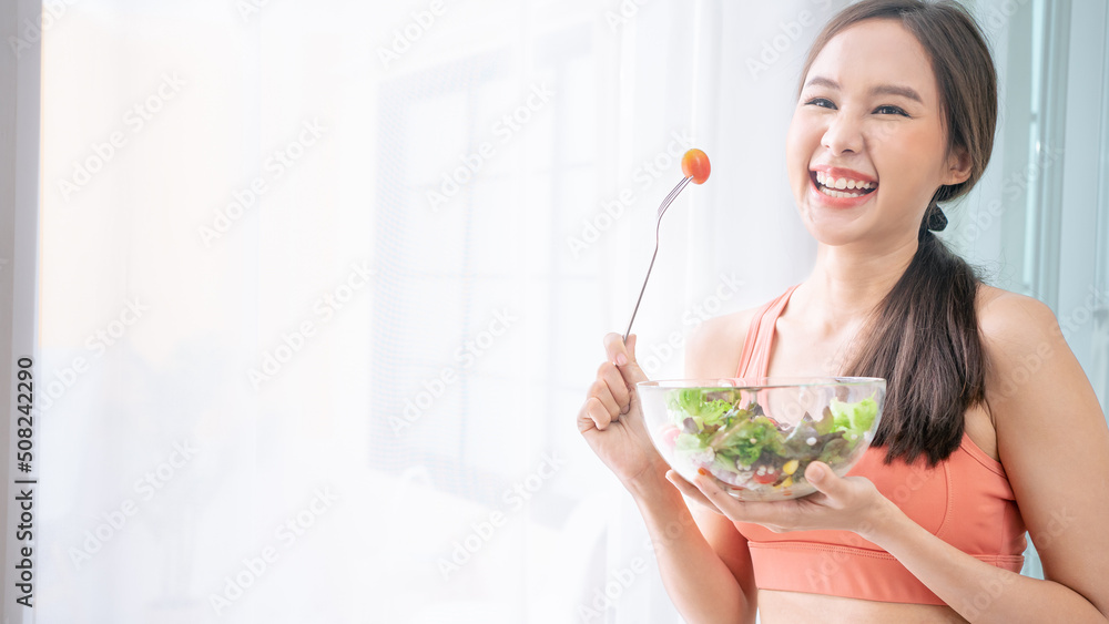 Portrait of Asian attractive woman hold salad bowl. Beautiful sport girl in sportswear enjoy eat clean vegetables after exercise for health in house.Diet and Healthy food concept.Banner cover design. Portrait of Asian attractive woman hold salad bowl. Beautiful sport girl in sportswear enjoy eat clean vegetables after exercise for health in house.Diet and Healthy food concept.Banner cover design.