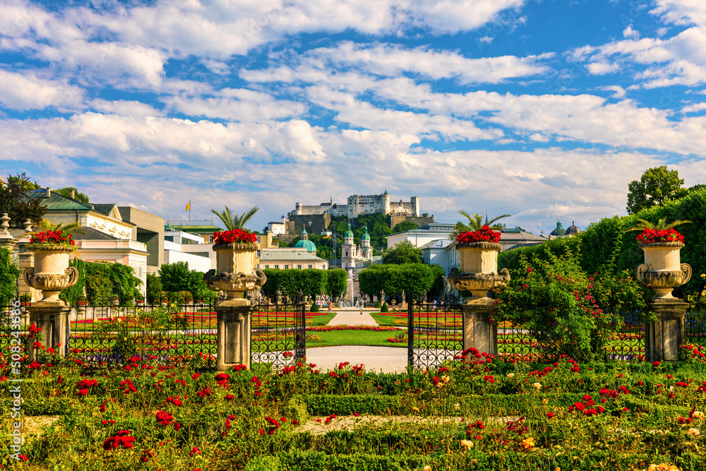 Beautiful view of famous Mirabell Gardens with the old historic Fortress Hohensalzburg in the background in Salzburg, Austria. Famous Mirabell Gardens with historic Fortress in Salzburg, Austria. - obrazy, fototapety, plakaty 